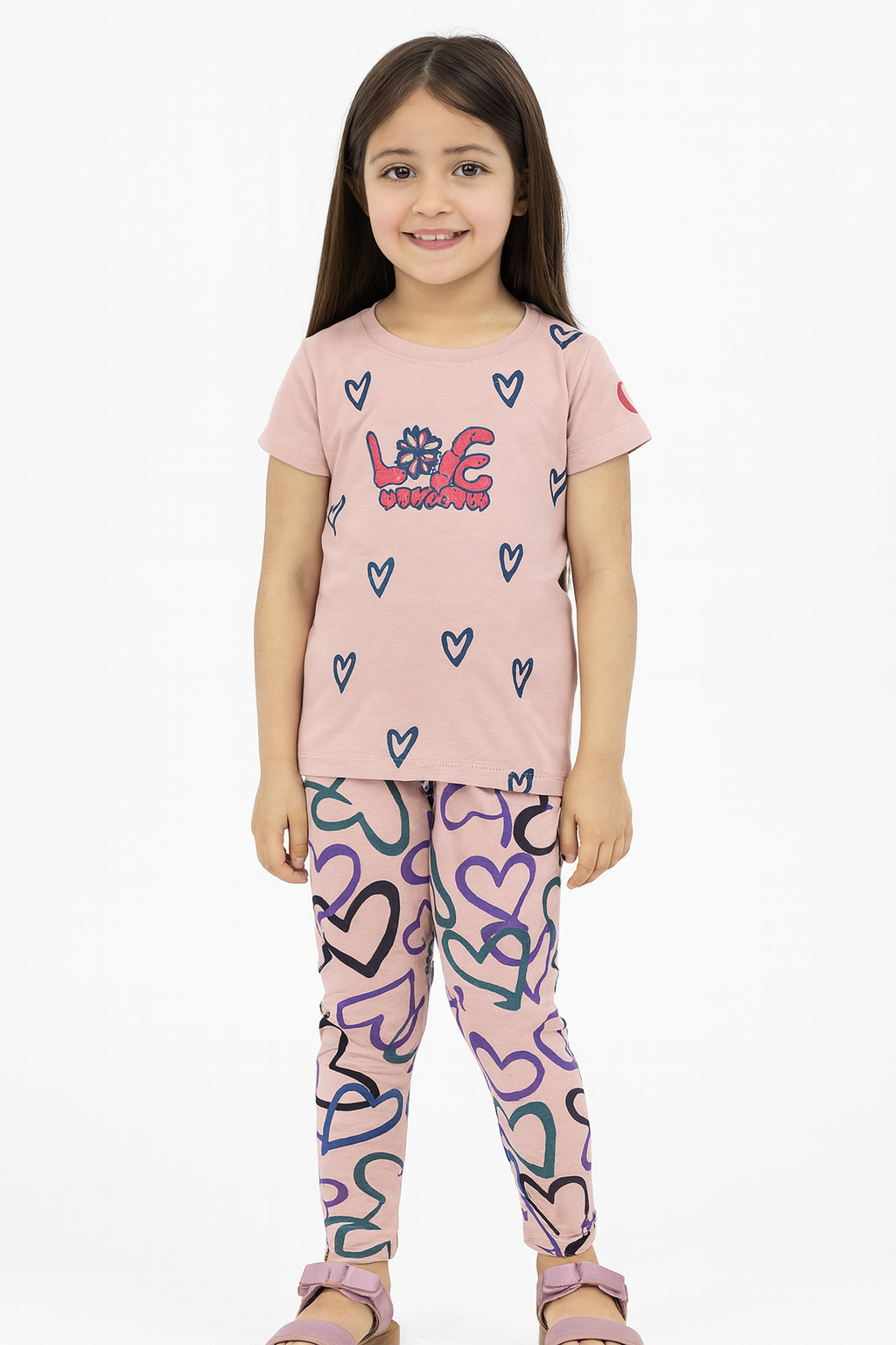 Young girl wearing a pink t-shirt and colorful leggings with heart designs on a white background