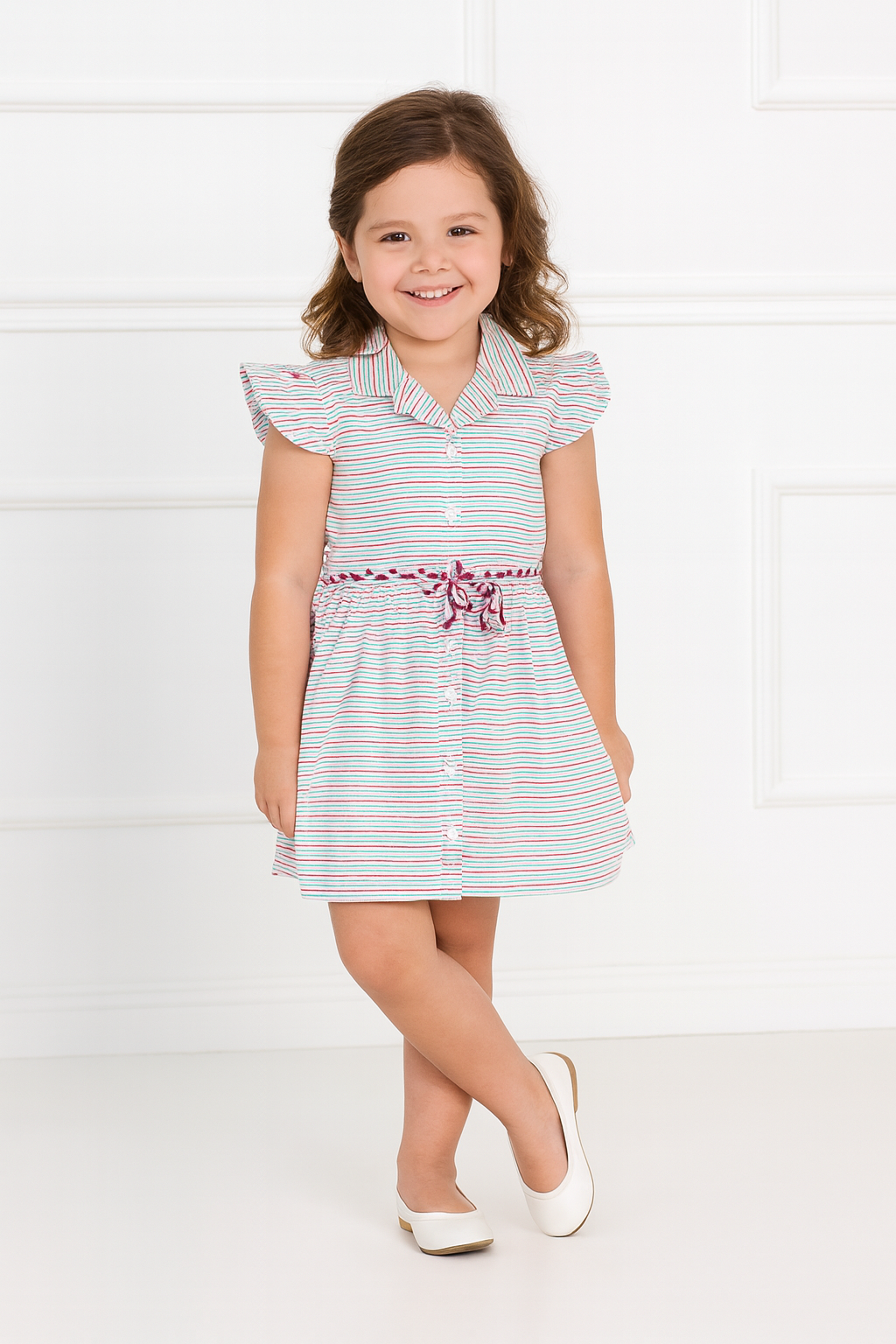 Young girl wearing a striped top with a floral belt against a white background