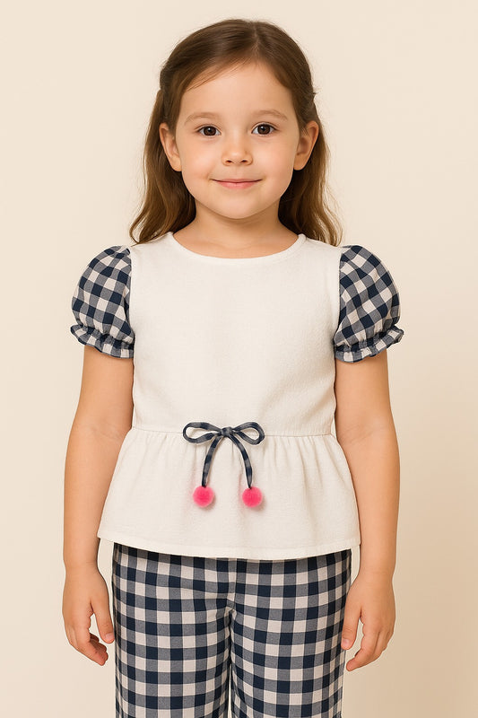 Young girl wearing a white top with checkered sleeves and plaid pants on a beige background
