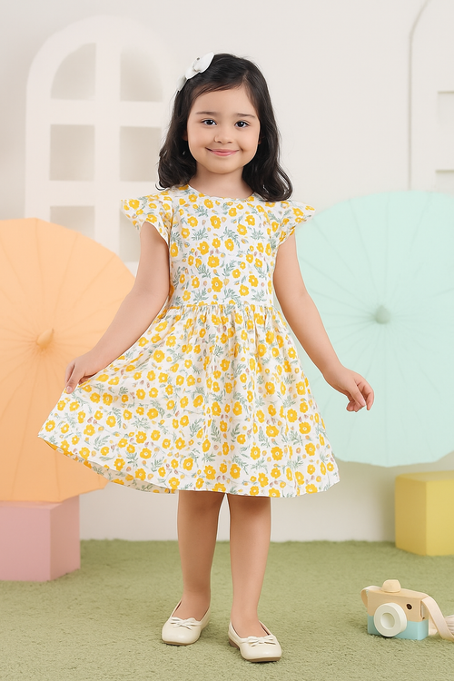 Young girl wearing a yellow floral dress in a colorful room.