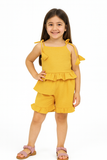 Young girl wearing a yellow outfit with ruffled top and shorts on a white background