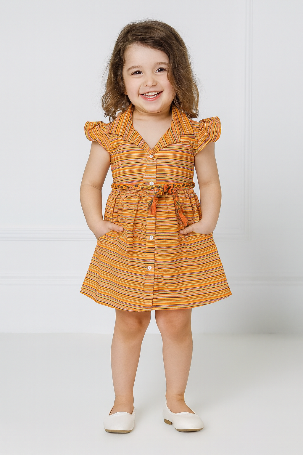 Young girl wearing an orange and yellow striped dress on a white background