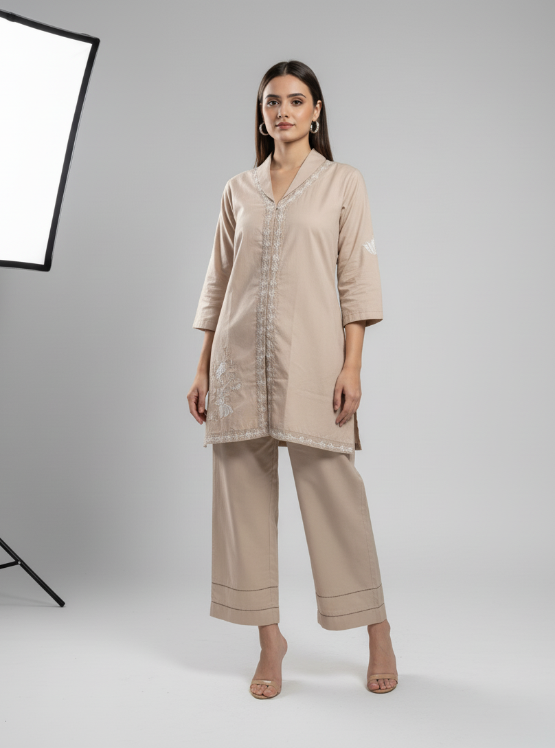 Woman wearing a beige outfit standing in front of a softbox light on a gray background