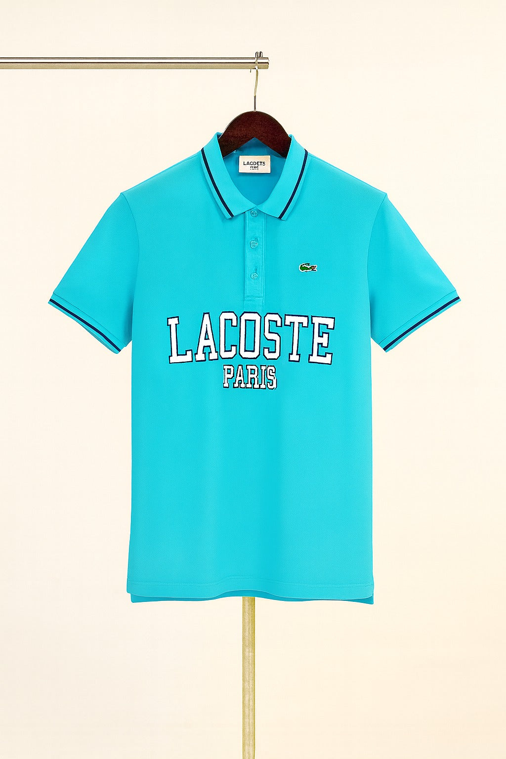 aqua Lacoste polo shirt on a hanger against a beige background
