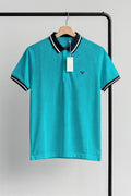 aqua polo shirt with black coller on a hanger against a gray background
