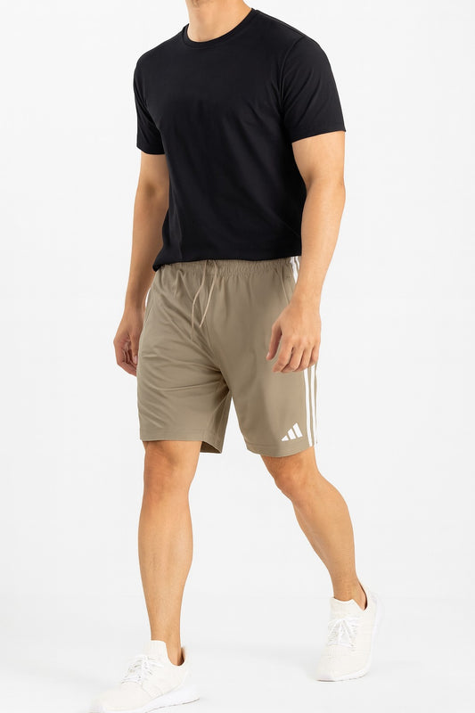 Person wearing a black t-shirt and beige Adidas shorts on a white background