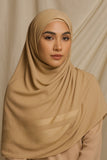 Woman wearing a beige hijab against a beige background