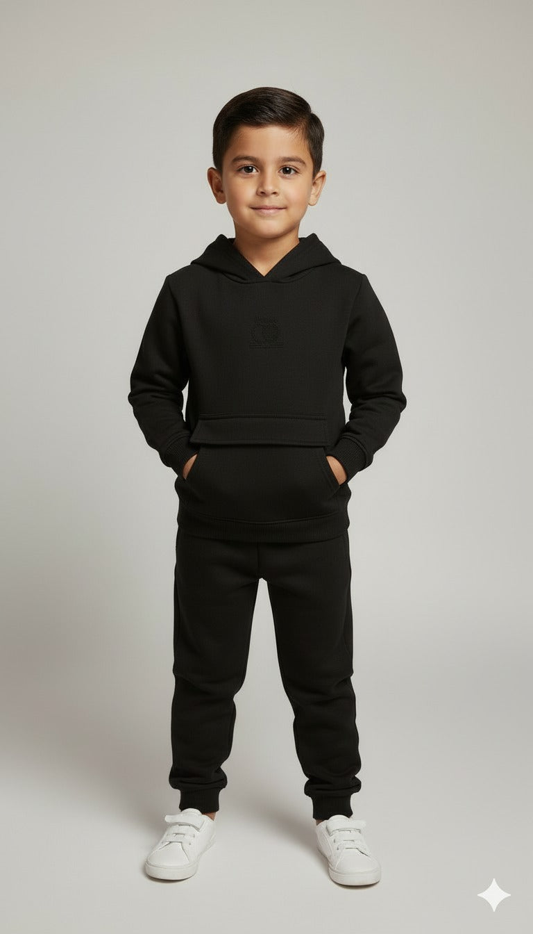Child wearing a black hoodie and pants on a plain background