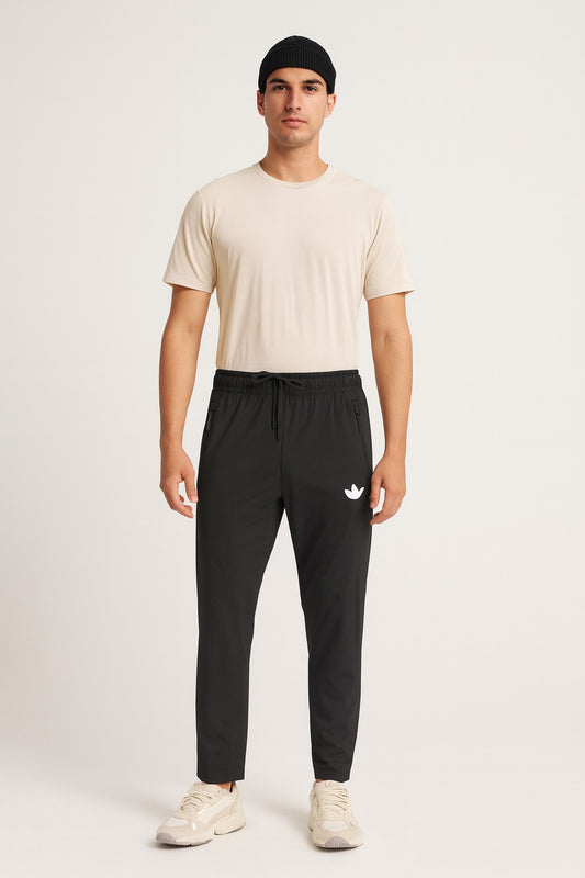 Man wearing a beige t-shirt and black pants with a logo on a white background