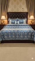 Decorative bedspread with blue and white patterns on a bed in a bedroom setting.