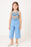 Young girl wearing a sleeveless top with a striped pattern and blue polka dot pants on a white background