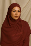 Woman wearing a brown hijab against a beige background