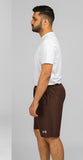 Man wearing a white shirt and brown shorts with a brand logo on a gray background