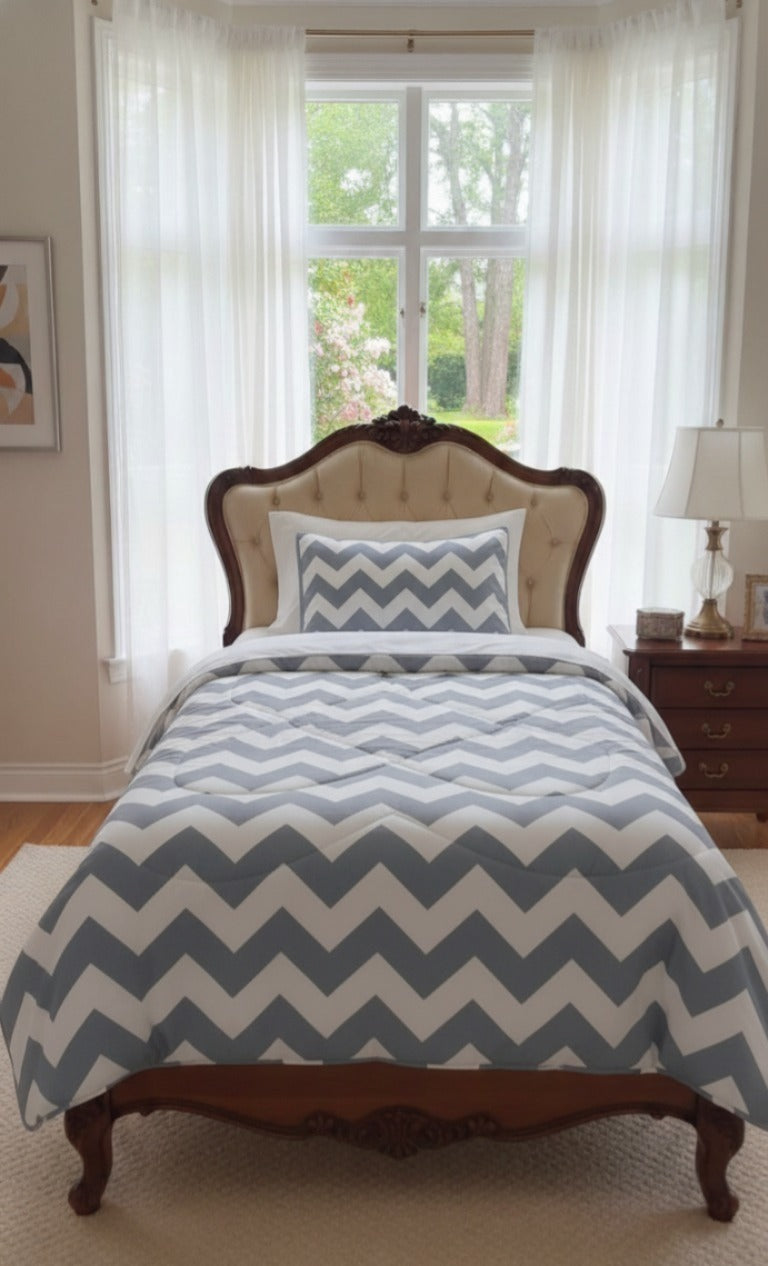 Bed with chevron patterned comforter in a room with a window and lamp.