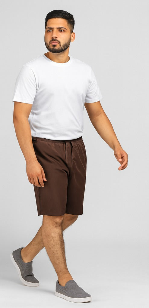 Man wearing a white t-shirt and brown shorts on a plain background