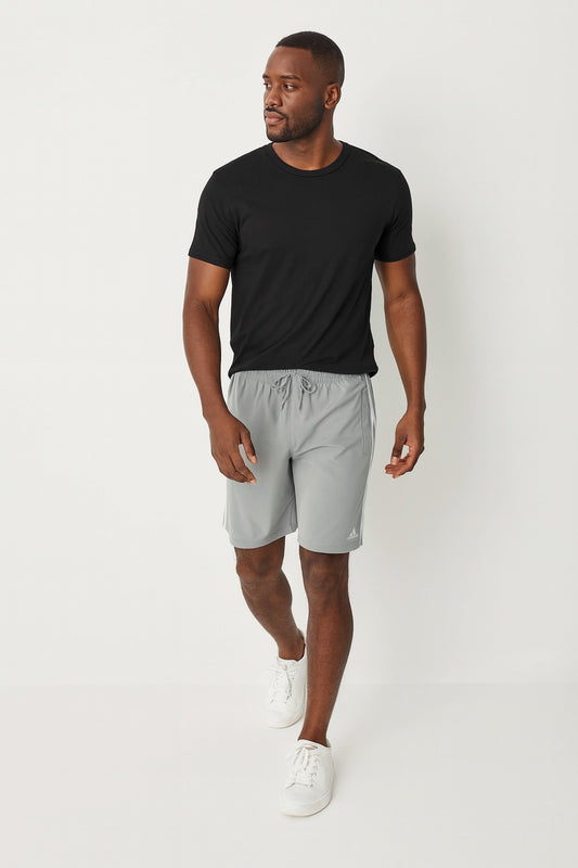 Man wearing a black t-shirt and gray shorts on a white background