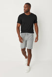 Man wearing a black t-shirt and gray shorts on a white background