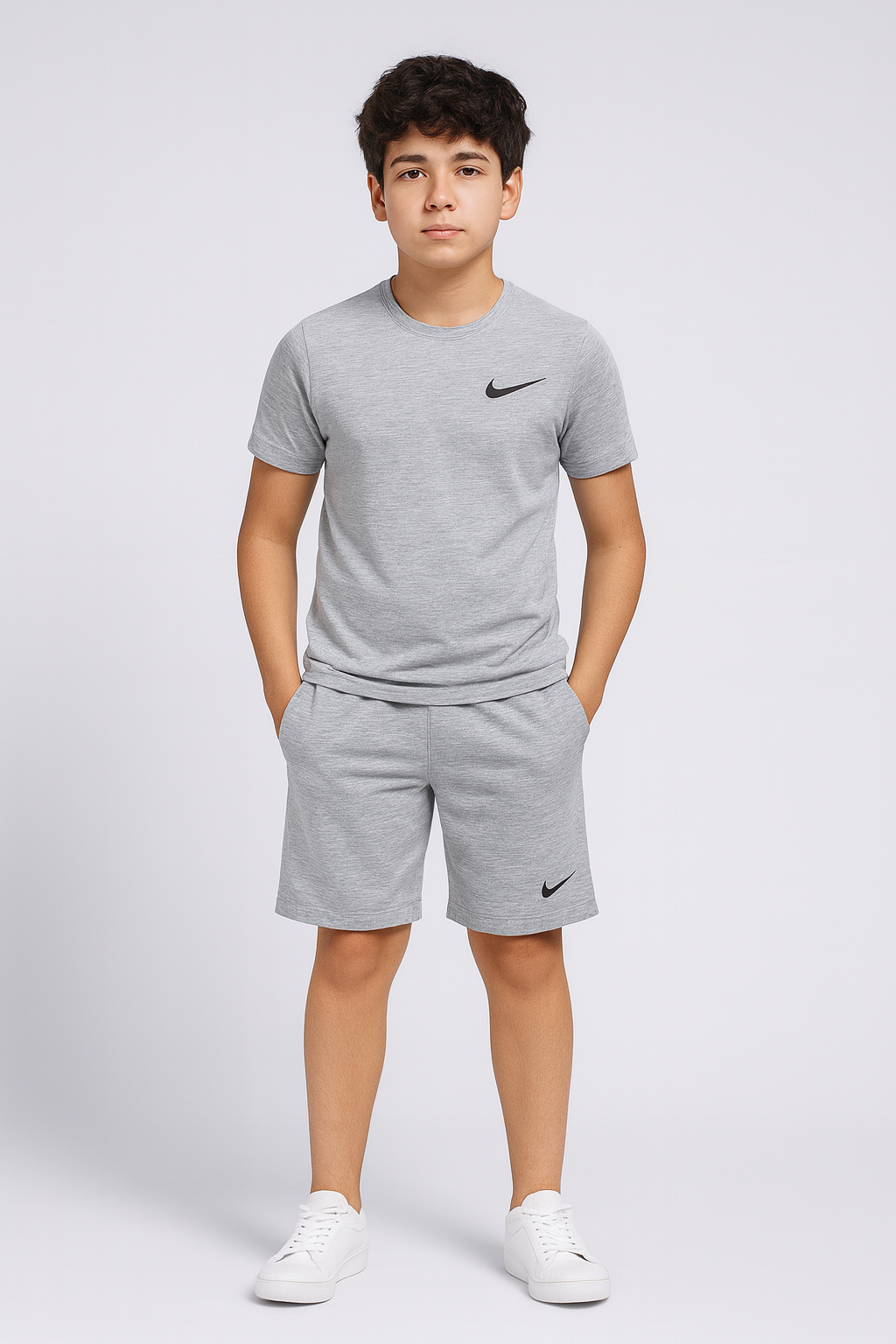 Young boy wearing a gray Nike t-shirt and shorts on a white background