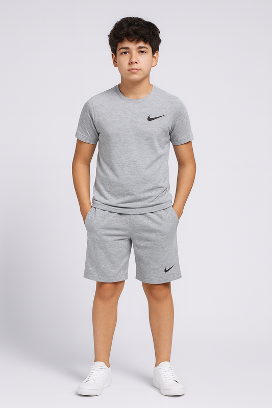Young boy wearing a gray Nike t-shirt and shorts on a white background