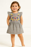 Child wearing a gray dress with floral embroidery on a white background