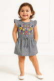 Child wearing a gray dress with floral embroidery on a white background
