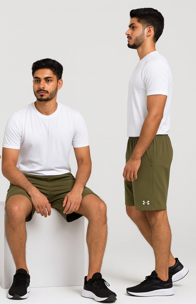 Two men wearing green shorts and white t-shirts, one sitting and one standing, on a white background.