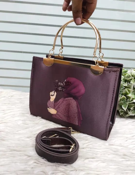 handbag with gold handles and a matching strap on a textured surface.