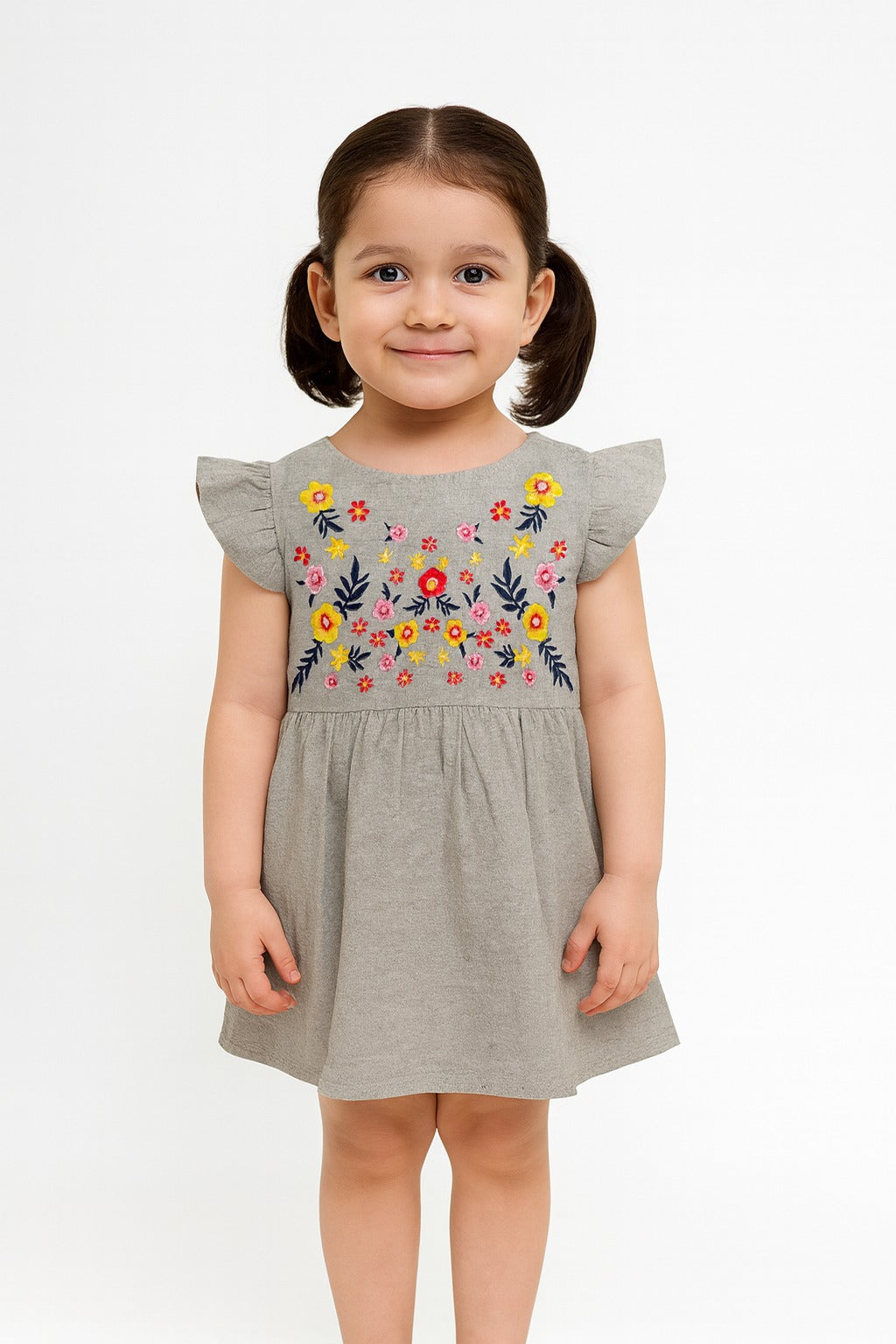Young girl wearing a gray dress with floral embroidery on a white background
