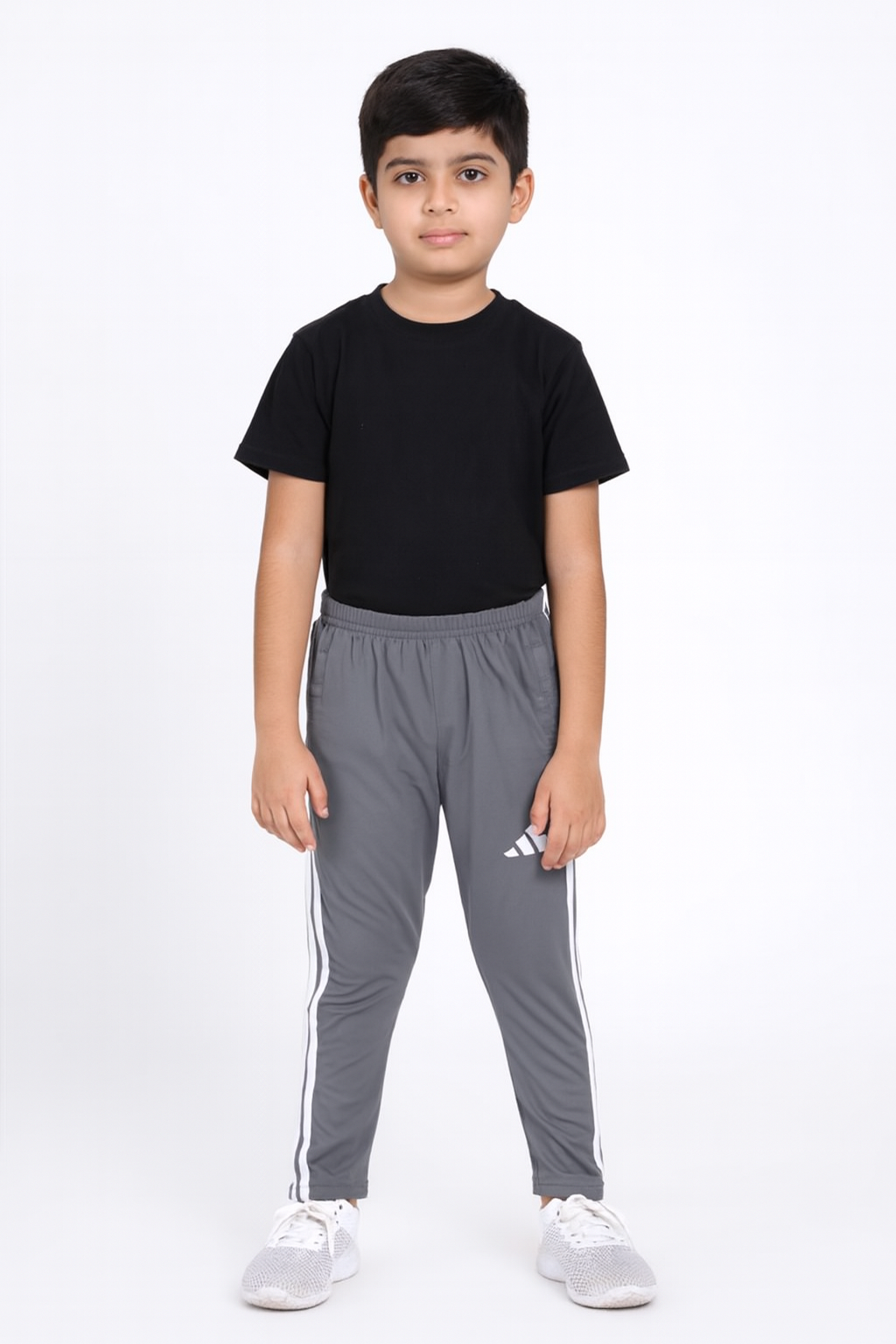 Child wearing a black t-shirt and gray tracksuit with white stripes on a white background