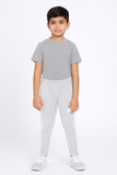 Child wearing a gray t-shirt and light gray pants on a white background