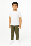 Child wearing a white t-shirt and green Adidas tracksuit pants on a white background