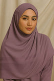 Woman wearing a mauve hijab against a beige background