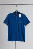 Blue polo shirt on a hanger against a gray background
