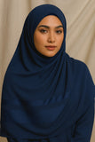 Woman wearing a navy blue hijab against a beige background