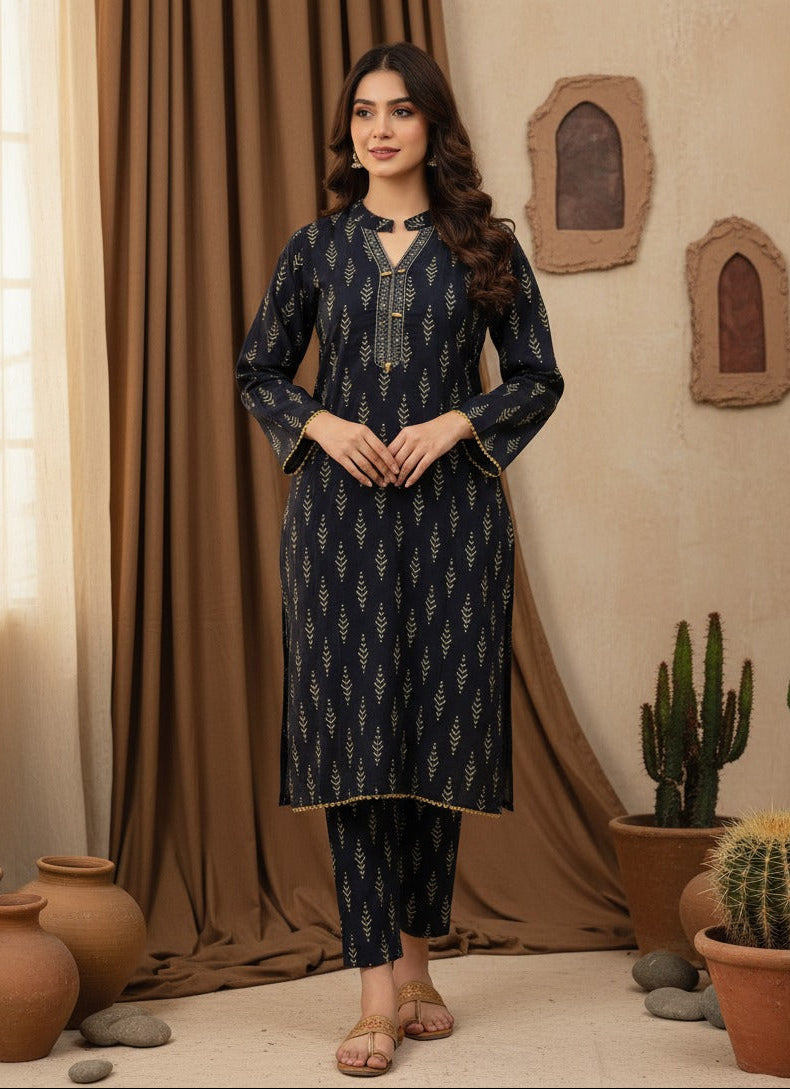 Woman in a navy blue patterned outfit standing in a room with plants and decor.