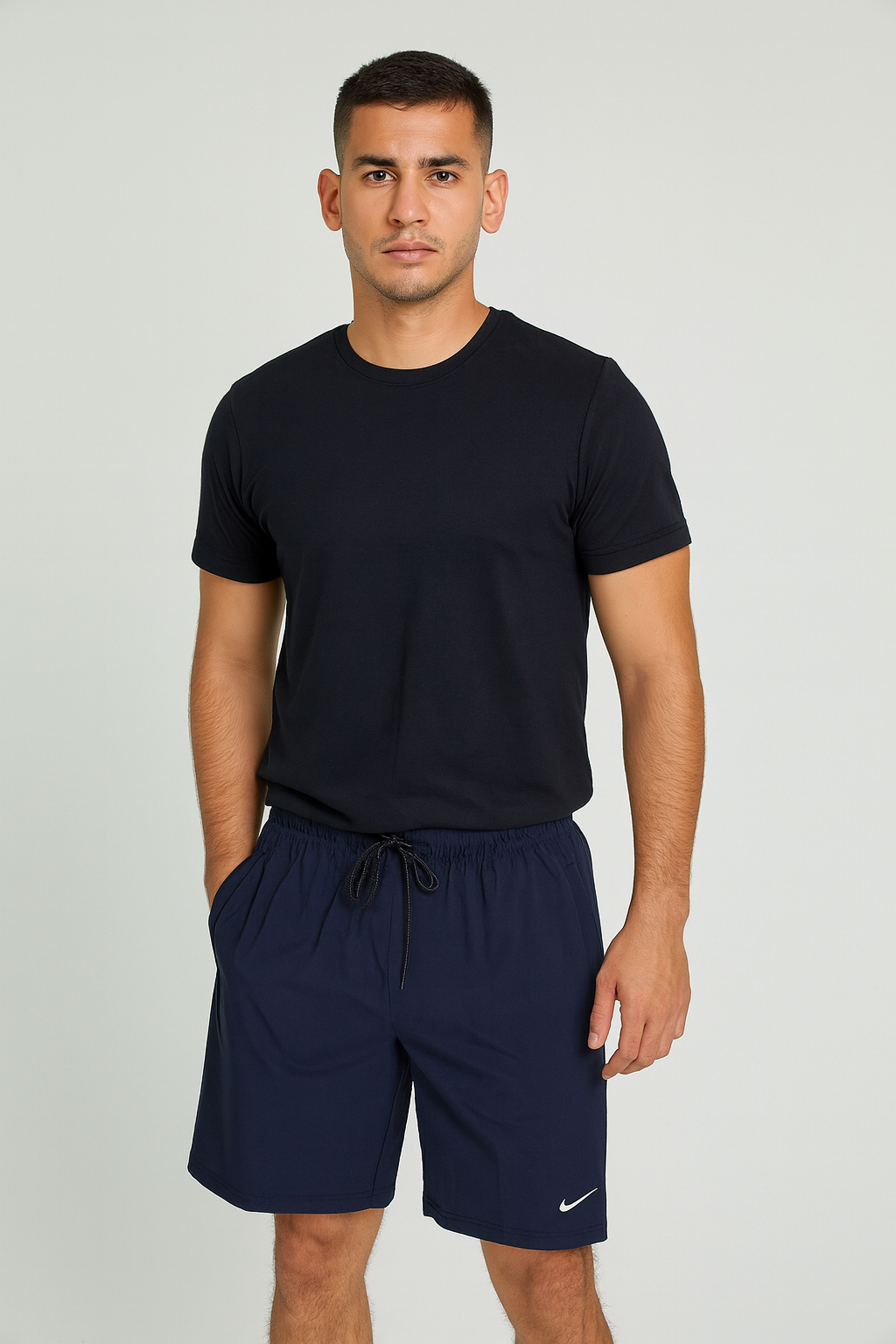 Man wearing a black t-shirt and navy shorts on a plain background