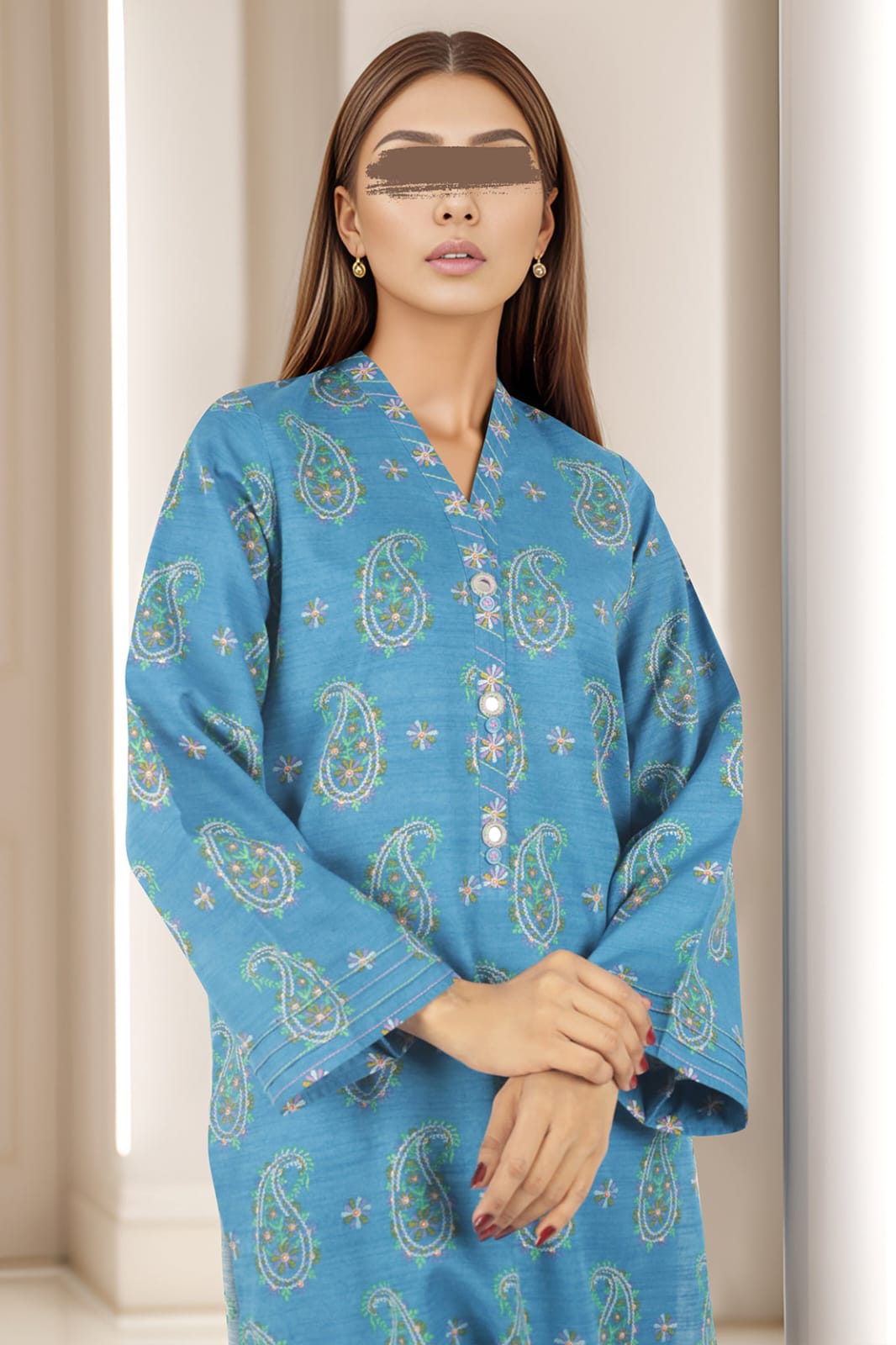 Woman wearing a blue paisley patterned outfit against a neutral background