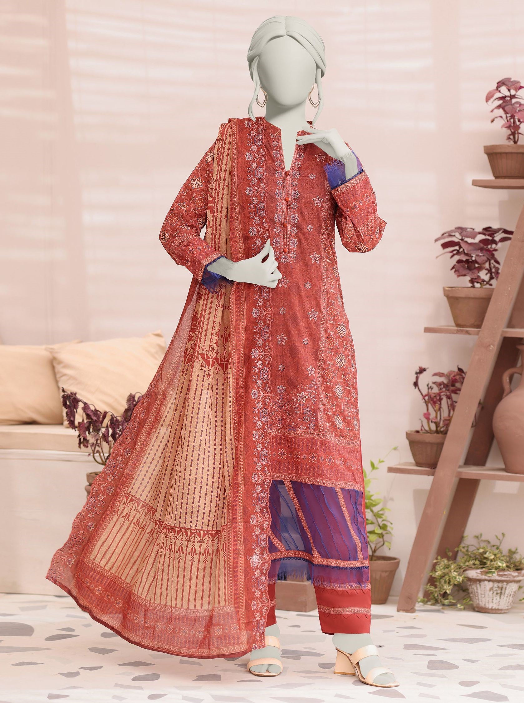 orange patterned kurta with matching dupatta on a mannequin against a home decor background.