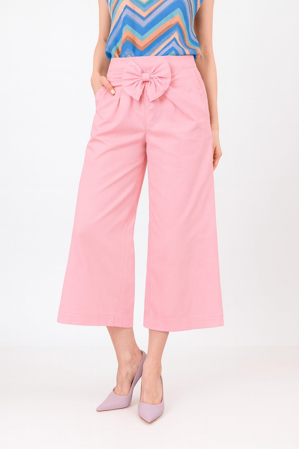 Person wearing pink pants with a bow detail on a white background