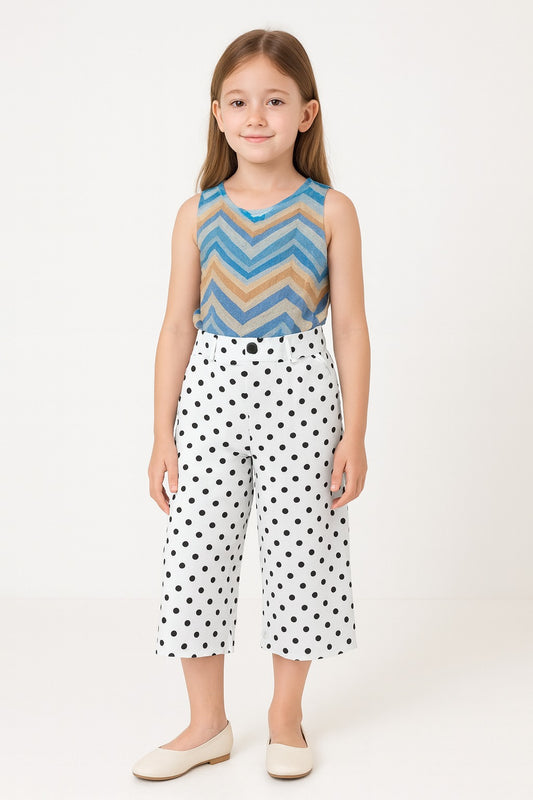 Young girl wearing a sleeveless top with a zigzag pattern and polka dot pants on a white background