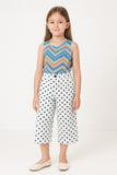 Young girl wearing a sleeveless top with a zigzag pattern and polka dot pants on a white background