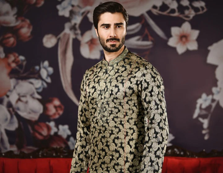 Man wearing a patterned outfit standing against a decorative floral background