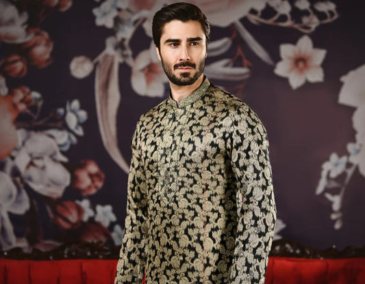 Man wearing a patterned outfit standing against a decorative floral background