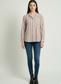Woman wearing a striped shirt and blue jeans on a white background